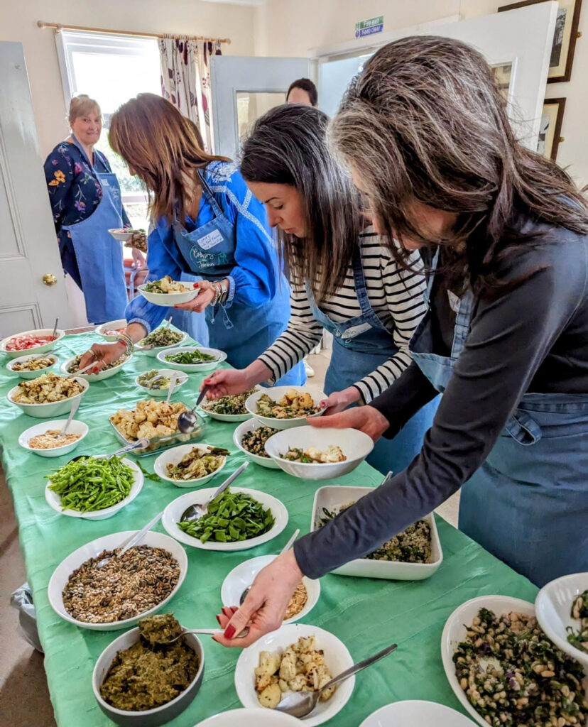 women in front of a buddha bowl buffet.